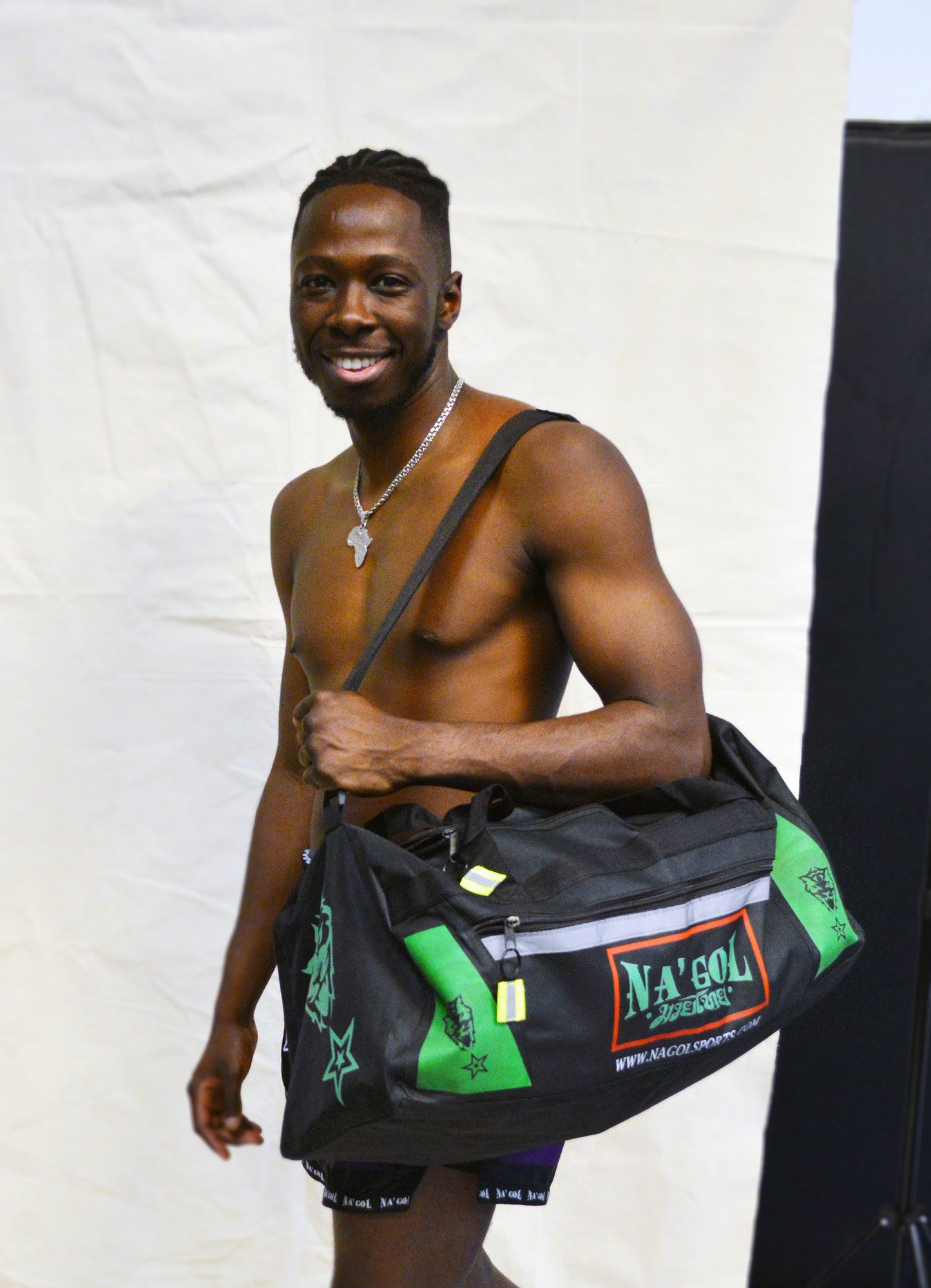 Man holding a black duffel bag with green accents against a white background